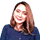 Seorang wanita tersenyum dengan rambut panjang yang tergerai, mengenakan kemeja navy. Latar belakangnya tampak bersih dan profesional, menciptakan suasana ramah.