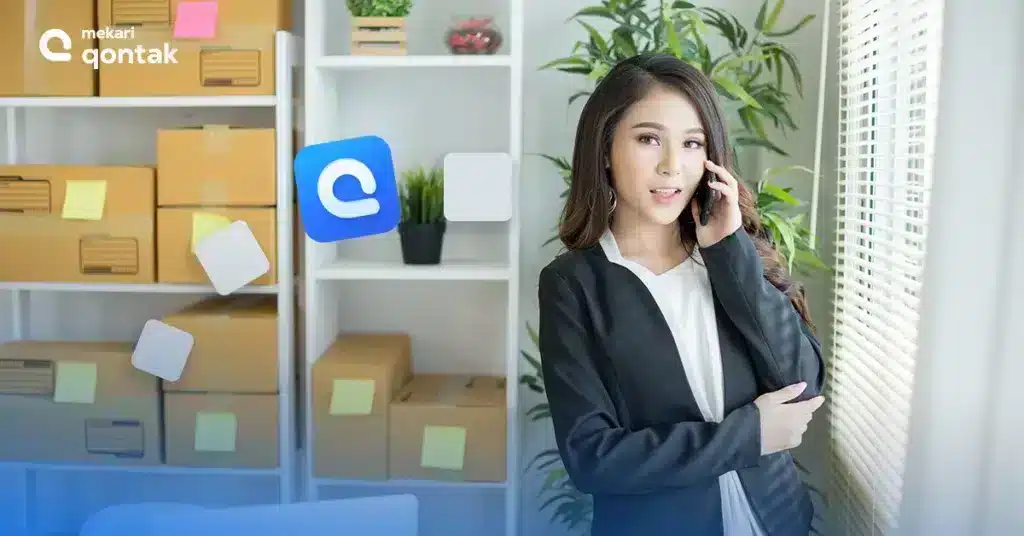 WhatsApp Business Solutions Provider Seseorang mengenakan blazer hitam berbicara di telepon, dikelilingi oleh kotak-kotak kemasan dan rak putih di ruang kerja yang rapi.