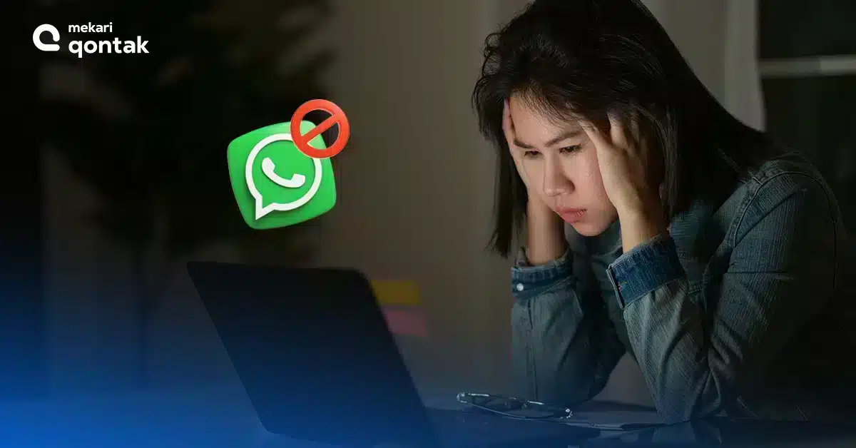Seorang wanita terlihat frustasi sambil memegang kepala, duduk di depan laptop dengan latar gelap, menunjukkan simbol larangan pada aplikasi WhatsApp.