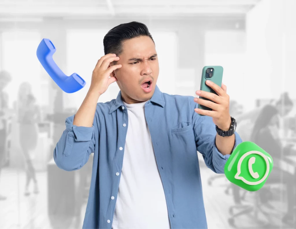 Seorang pria memegang ponsel sambil menunjukkan ekspresi bingung, dikelilingi ikon telepon dan WhatsApp, dalam suasana kantor yang sibuk.