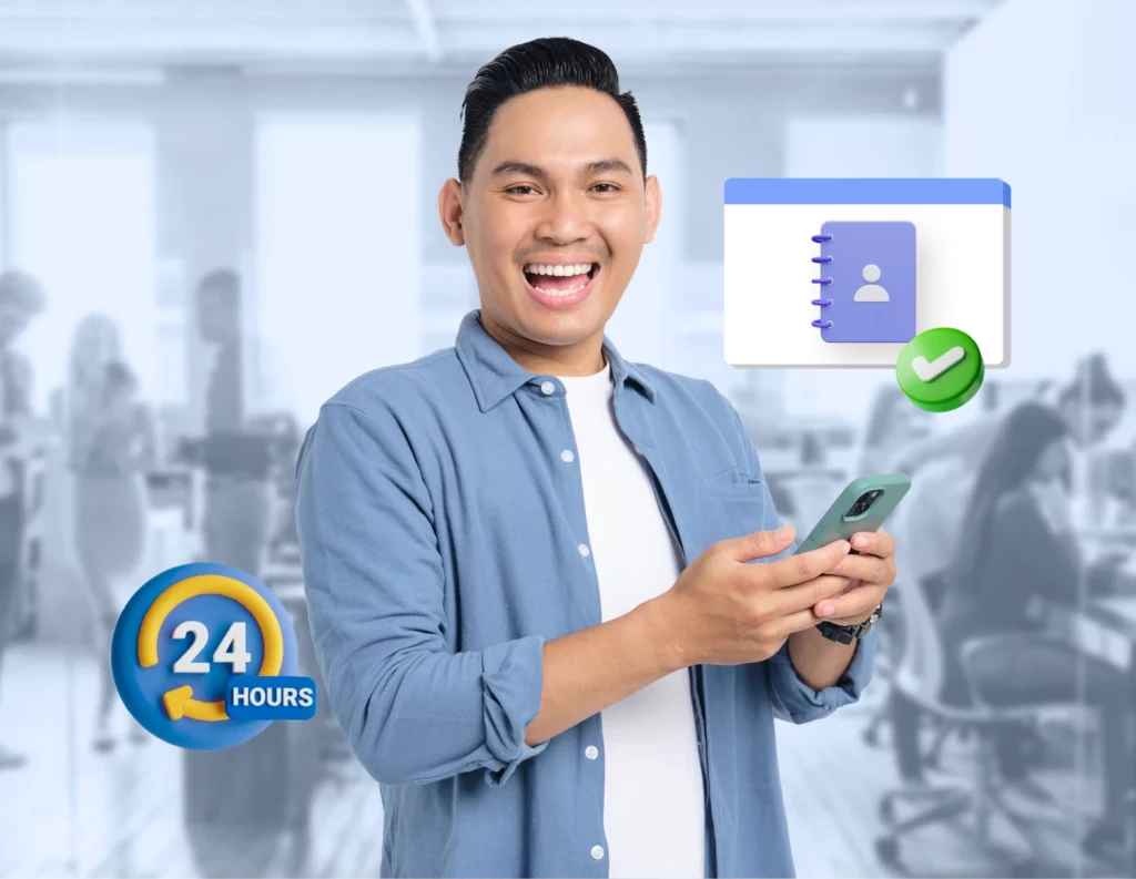 Seseorang memegang ponsel sambil tersenyum, menggunakan aplikasi kontak di lingkungan kantor yang sibuk, dengan simbol waktu 24 jam di bawahnya.